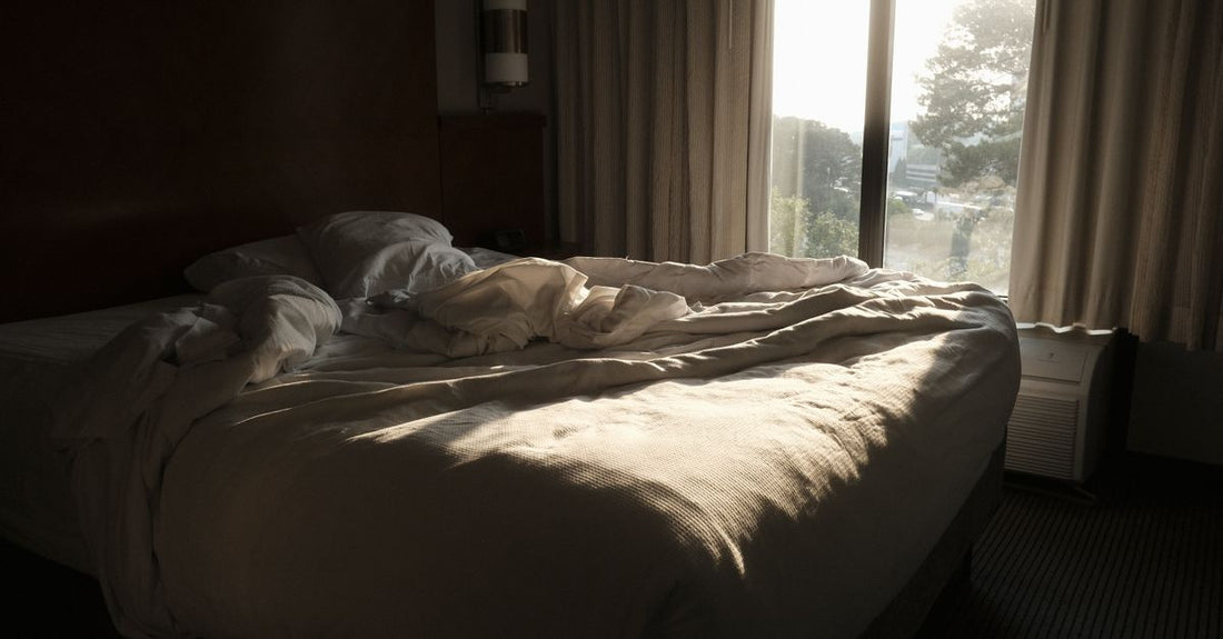 A comfortable bed in a bedroom with soft morning sunlight illuminating the room